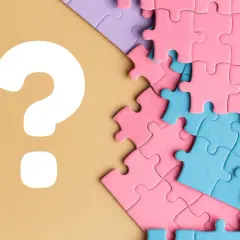 Kolorowe puzzle, różowe i niebieskie, czekają na ułożenie. Czy to będzie idealne puzzle dla chłopca? Wielkie białe znaki zapytania sugerują zagadkę.