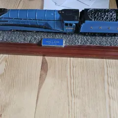 Niebieska lokomotywa parowa zabawka "Mallard" na drewnianej podstawie.