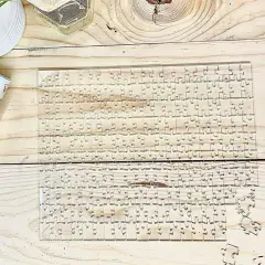 Przezroczyste, trudne puzzle na drewnianym blacie. Kilka elementów leży obok.