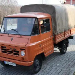 Pomarańczowy żuk z plandeką, gotowy do transportu towarów.