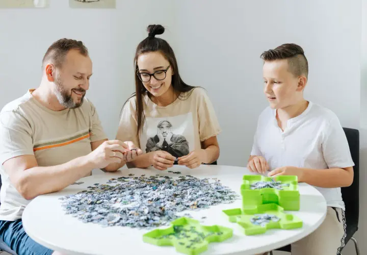 Rodzina wspólnie układa puzzle, ucząc się, jak szybko układać puzzle.