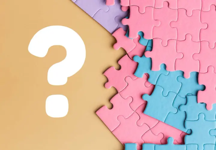 Kolorowe puzzle, różowe i niebieskie, czekają na ułożenie. Czy to będzie idealne puzzle dla chłopca? Wielkie białe znaki zapytania sugerują zagadkę.