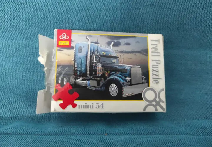 Pudełko z mini puzzlami przedstawiające niebieską ciężarówkę z chromowanymi detalami. Idealne dla miłośników motoryzacji i układania.
