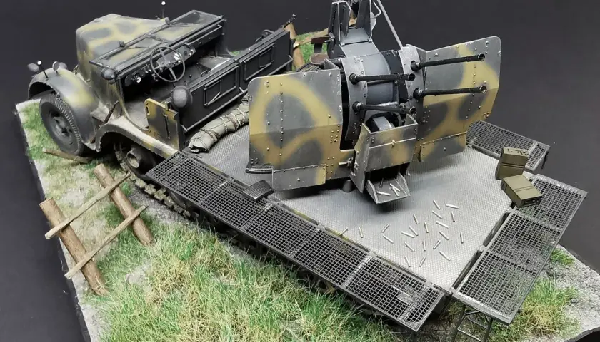 Model pojazdu z działkiem flakvierling 38, gotowy do akcji na trawiastym podłożu, z widocznymi łuskami.