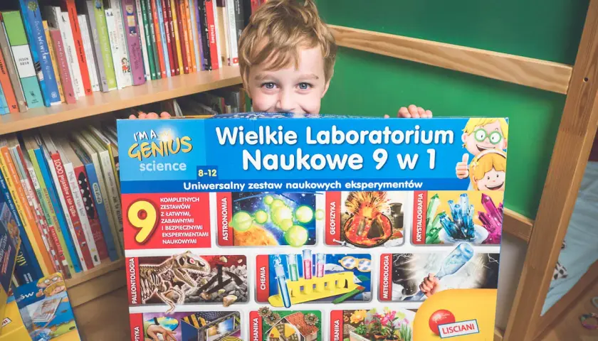 Chłopiec z radością prezentuje zestaw naukowych gadżetów "Wielkie Laboratorium Naukowe 9 w 1", gotowy do odkrywania tajemnic nauki.