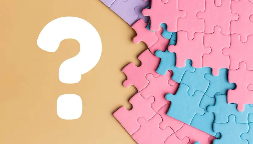 Kolorowe puzzle, różowe i niebieskie, czekają na ułożenie. Czy to będzie idealne puzzle dla chłopca? Wielkie białe znaki zapytania sugerują zagadkę.