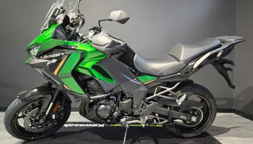 Zielony motocykl Kawasaki Versys 1100, jeden z wielu modeli tej marki, gotowy na przygodę.