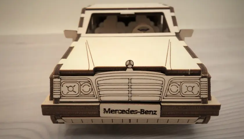 Drewniane puzzle w kształcie klasycznego Mercedesa. Model z wygrawerowanym napisem "Mercedes-Benz" na tablicy rejestracyjnej.