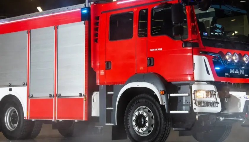 Nowoczesny model wozu strażackiego MAN, lśniący czerwienią, gotowy do akcji.