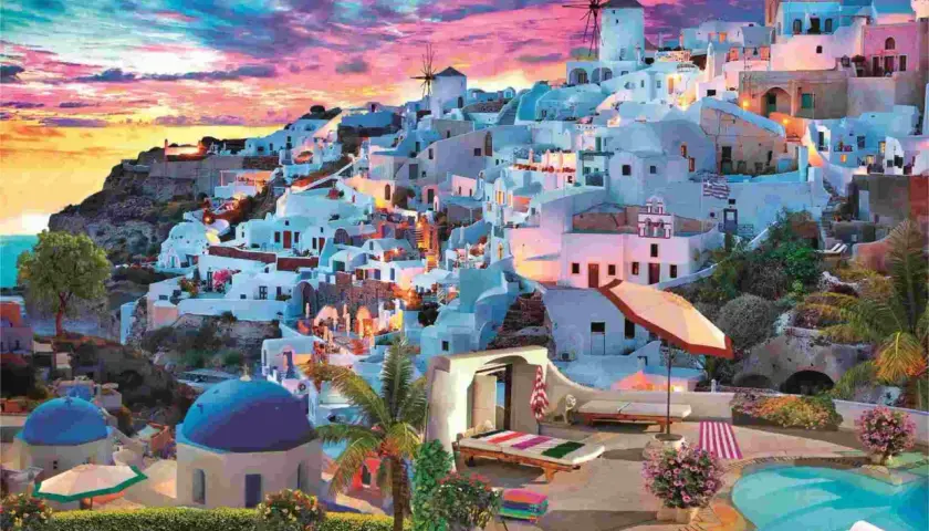 Widok na Santorini o zachodzie słońca, białe domy na klifie, wiatraki, basen i leżaki. Ten puzzle santorini przeniesie Cię w podróż.