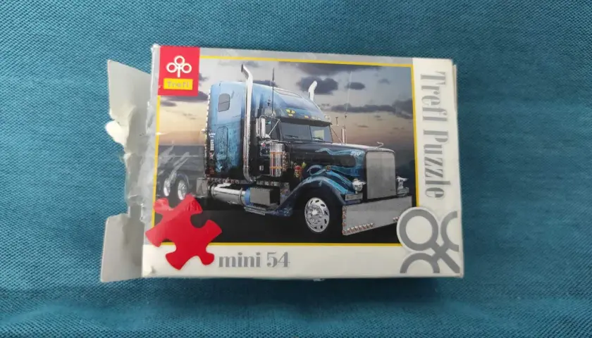 Pudełko z mini puzzlami przedstawiające niebieską ciężarówkę z chromowanymi detalami. Idealne dla miłośników motoryzacji i układania.