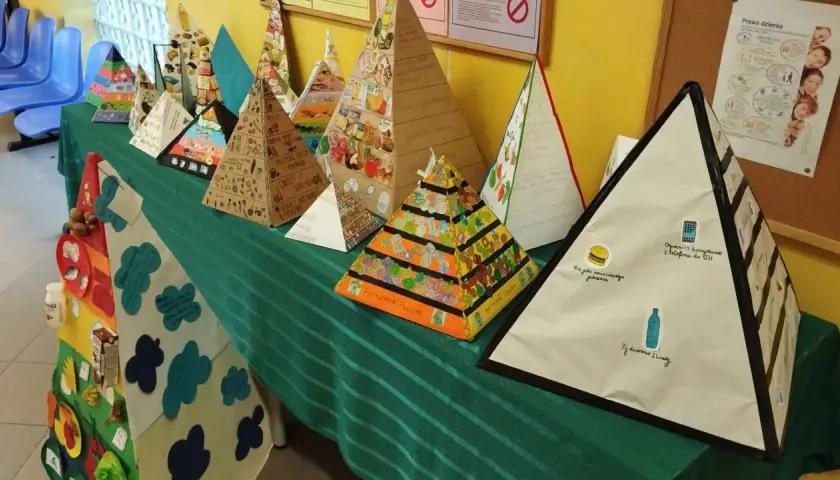 Wiele kolorowych piramid 3d, przedstawiających piramidę żywienia i zdrowego stylu życia, ozdobionych rysunkami i napisami.