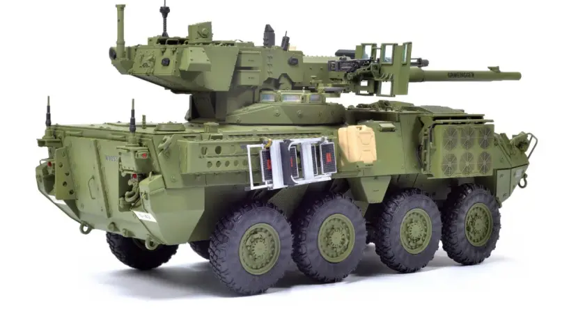 M1128 Stryker, zielony pojazd opancerzony z wieżyczką, działkiem i karabinem maszynowym, gotowy do akcji.