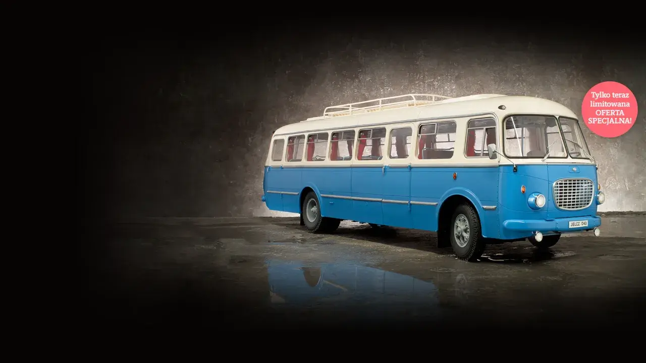 Niebiesko-biały autobus ogórek z bagażnikiem dachowym, stojący na mokrej nawierzchni.