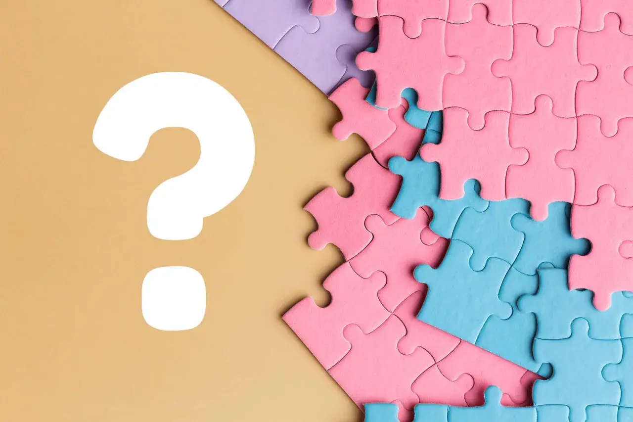 Kolorowe puzzle, różowe i niebieskie, czekają na ułożenie. Czy to będzie idealne puzzle dla chłopca? Wielkie białe znaki zapytania sugerują zagadkę.