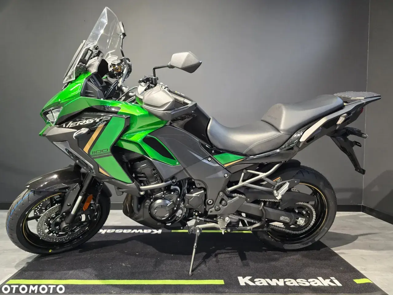 Zielony motocykl Kawasaki Versys 1100, jeden z wielu modeli tej marki, gotowy na przygodę.