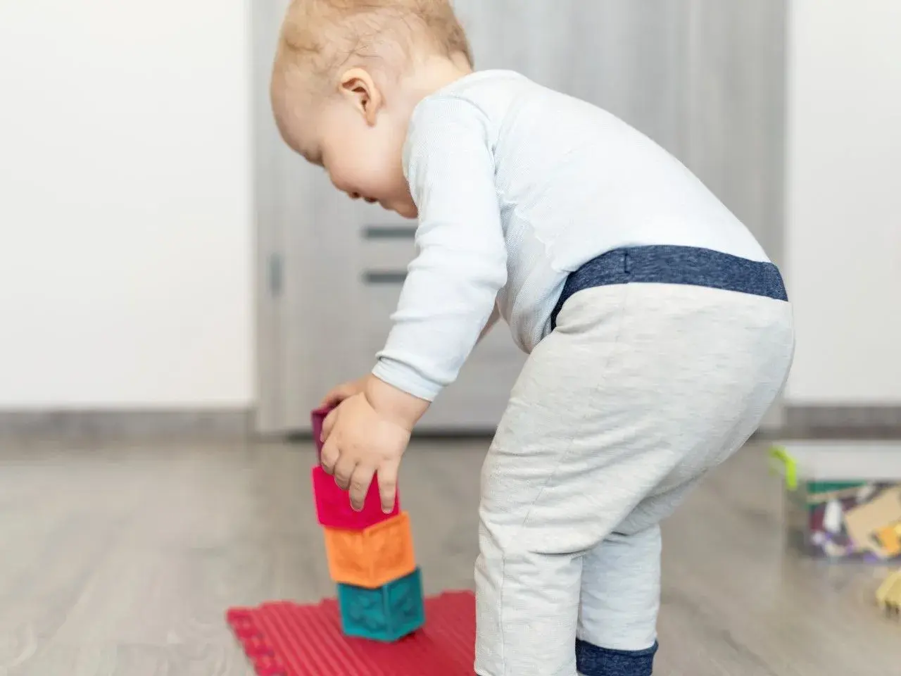 Małe dziecko buduje wieżę z kolorowych klocków ceramicznych.