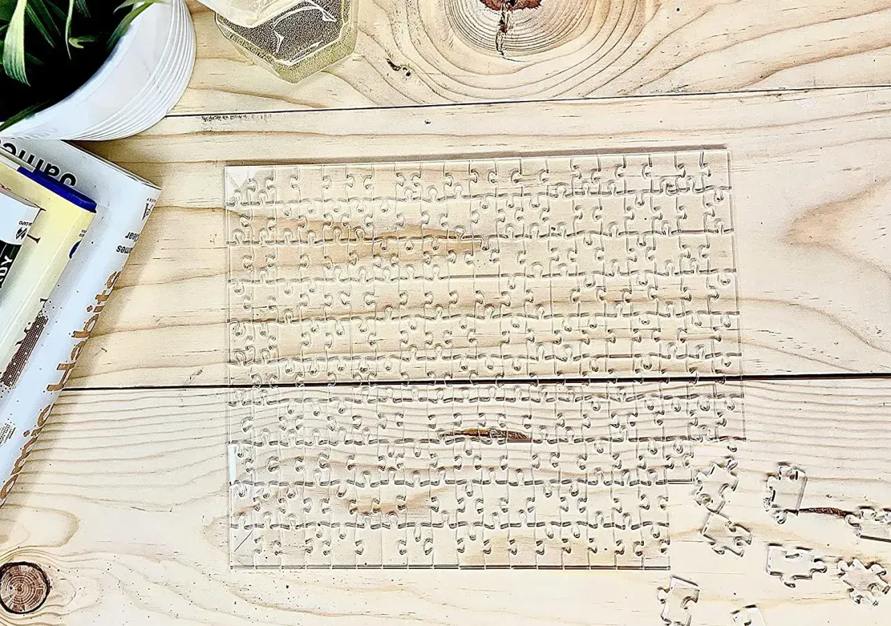 Przezroczyste, trudne puzzle na drewnianym blacie. Kilka elementów leży obok.