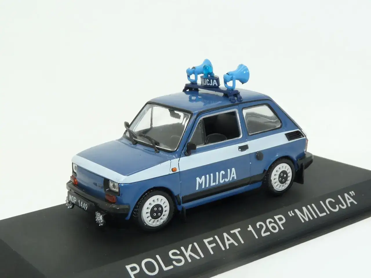 Niebieski samochód milicja Fiat 126p z niebieskimi syrenami na dachu.
