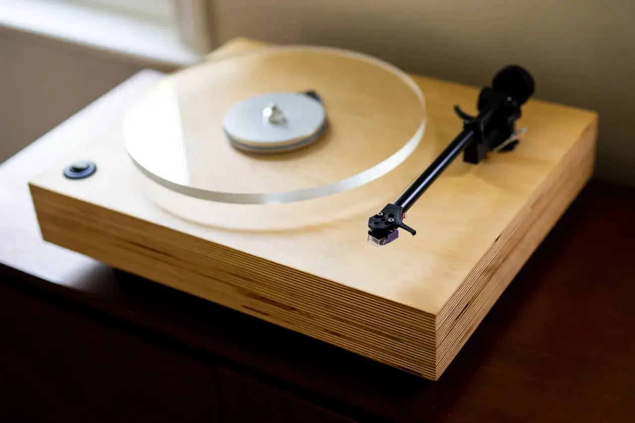 Elegancki gramofon drewniany z przezroczystym talerzem i czarnym ramieniem.