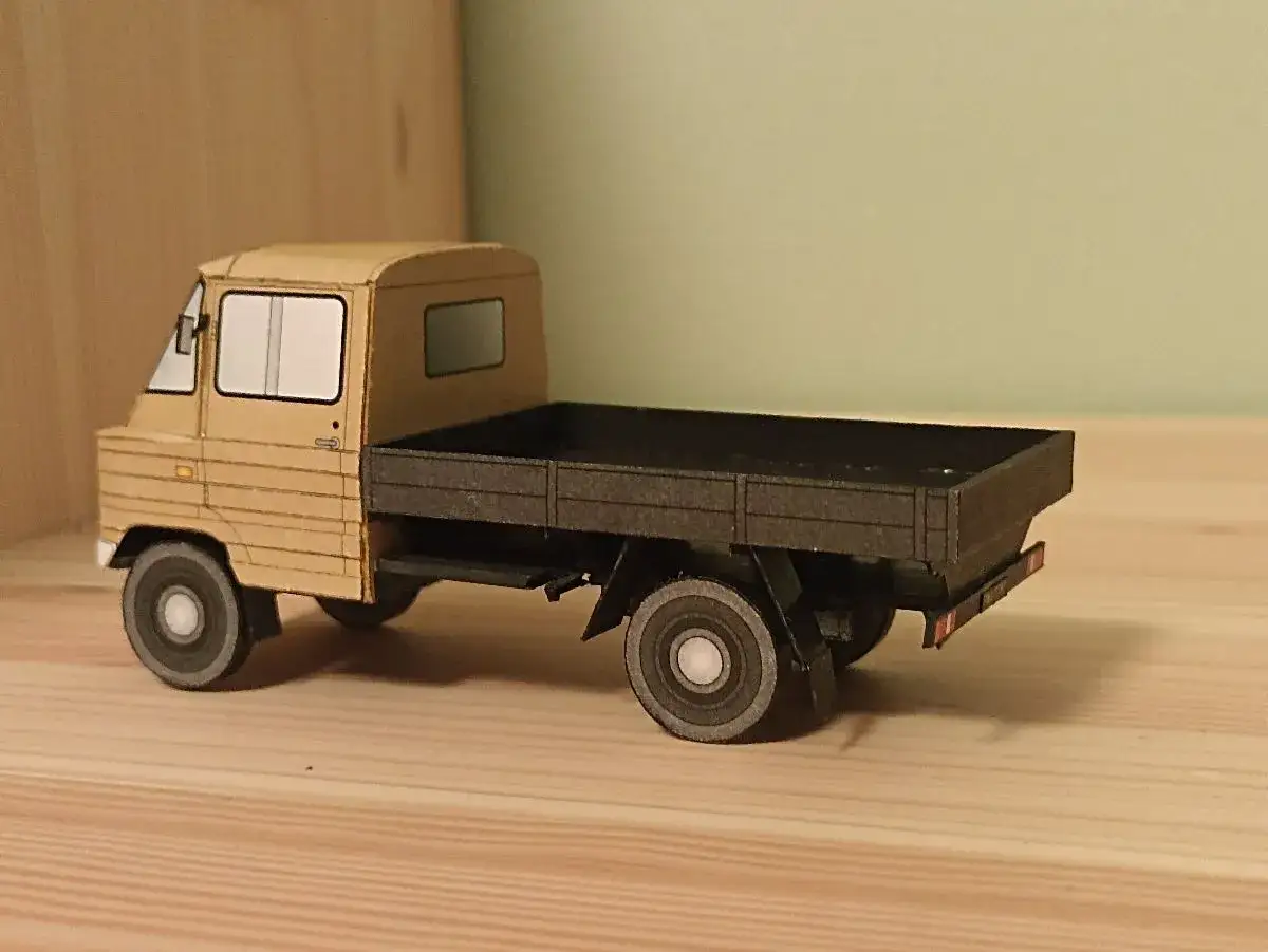 Model żuka z plandeką, wykonany z papieru, stoi na drewnianym blacie.