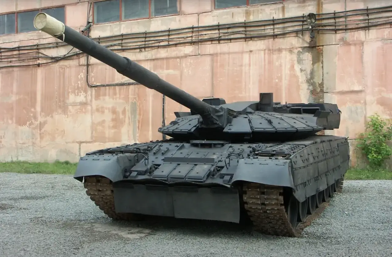 Czołg T-72B3, znany jako obiekt 640, z długą lufą i charakterystycznym pancerzem, stoi na żwirowym podłożu przed zniszczonym budynkiem.