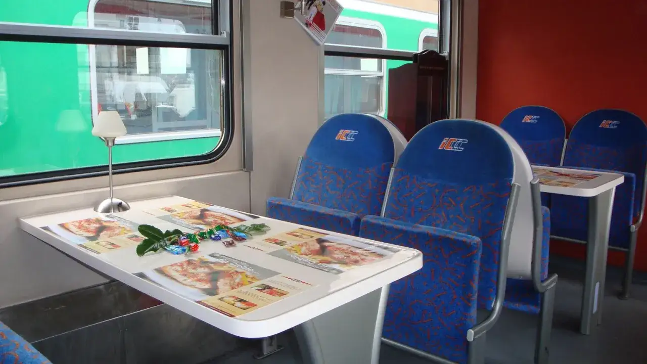 Wnętrze intercity wagon restauracyjny z niebieskimi siedzeniami i stolikiem z menu.