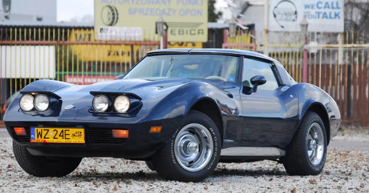 Granatowy klasyk, jeden z wielu pięknych corvette modele, błyszczy na tle ogrodzenia.