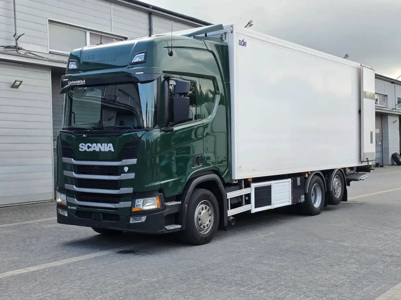 Zielona Scania R450 z białym kontenerem, gotowa do transportu.
