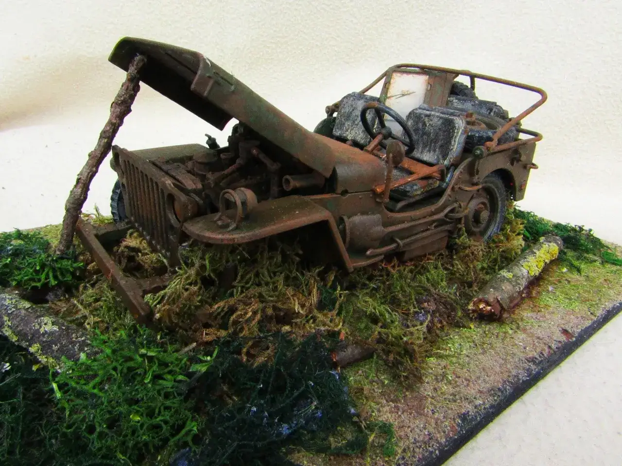 Zardzewiały jeep z przyczepą, porzucony w zaroślach, z otwartą maską i widocznym silnikiem.