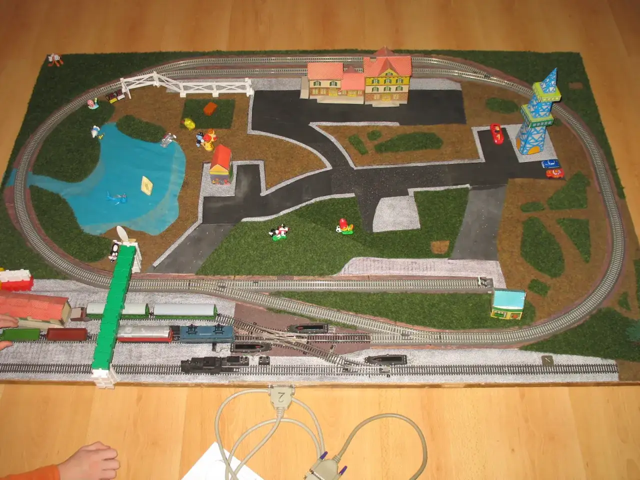 Miniaturowa kolej żelazna z budynkami, jeziorem i figurkami.