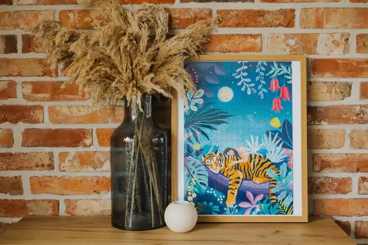 Ukończone puzzle na ścianie przedstawiają tygrysa śpiącego z dziewczynką na grzbiecie w nocnej, tropikalnej scenerii.